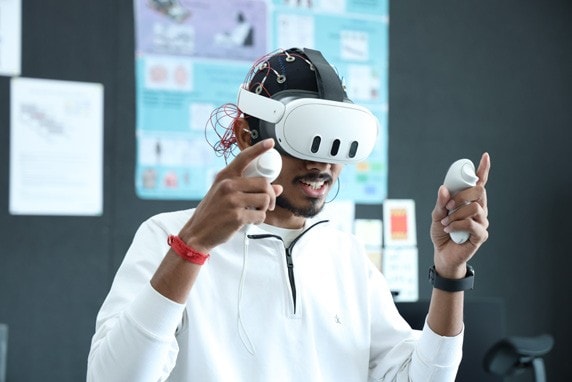 A student exploring a VR headset fitted with brain sensors